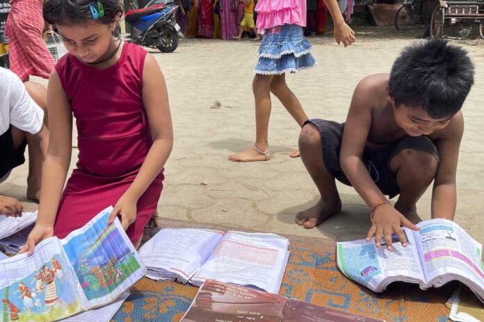 Flood-affected children check their textbooks that were kept to dry under the sun at a relief shelter