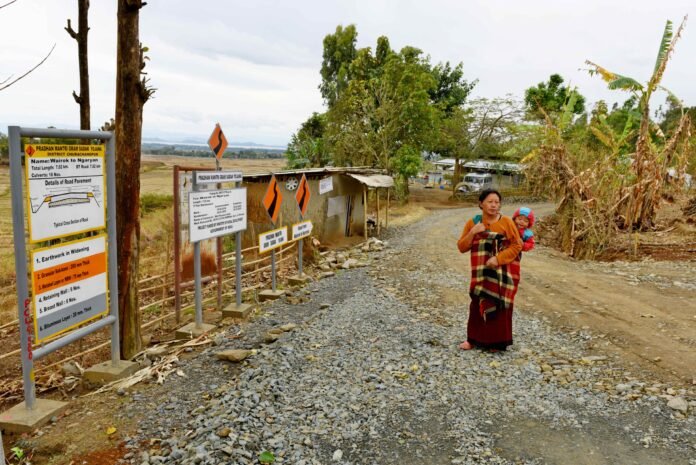 A mother carries her child along an unfinished rural road in Ngaryan Village, Manipur