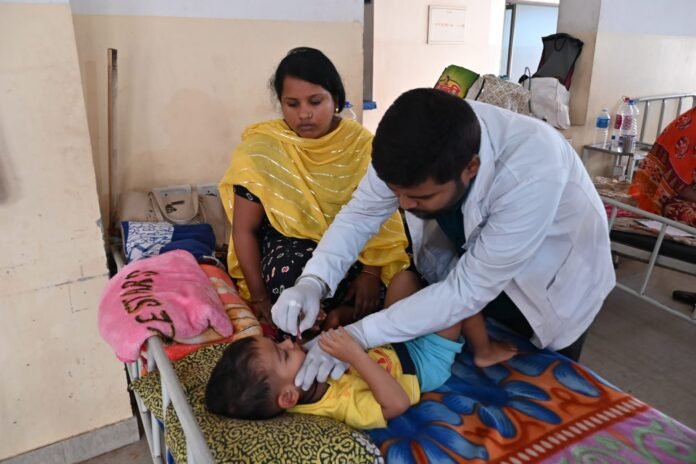 Healthcare workers and mother with infant at Tripura medical facility reflecting improved child health outcomes.