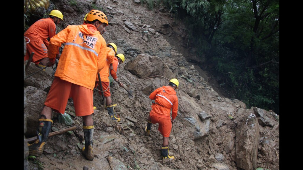 Rescue teams near the site of the Migging Landslide Fatalities Incident after a vehicle plunged down a steep hillside.