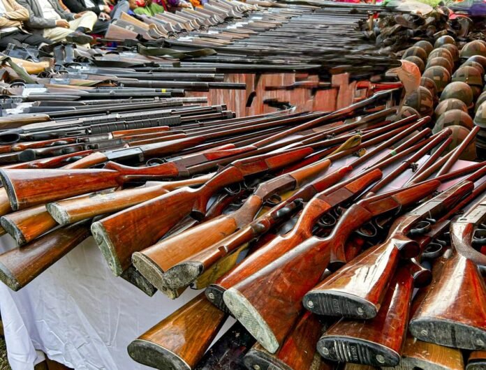 Security personnel display seized weapons, explosive materials, and documents recovered during an intelligence-based operation at a suspected hideout.