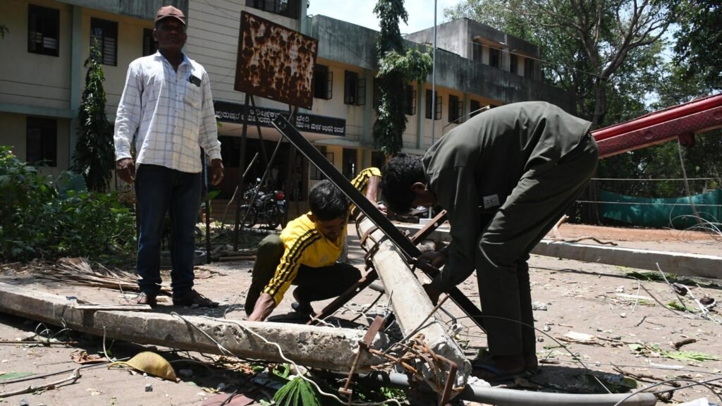 Emergency electricity crews repair damaged transmission towers after uprooted trees disrupted power supply during severe monsoon weather.