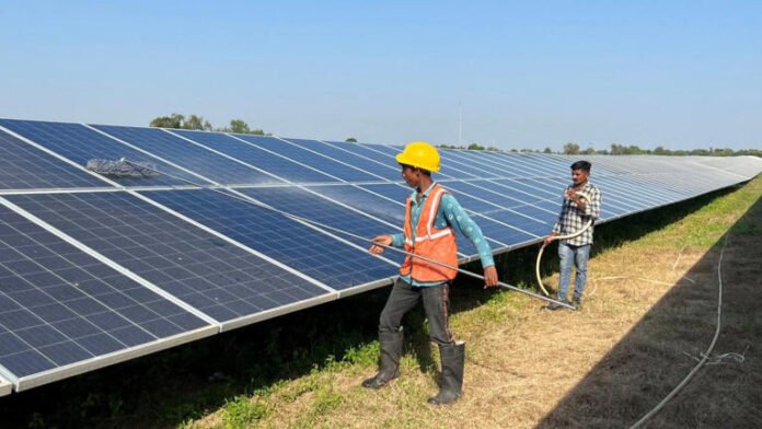 Workers clean panels at a solar park in Modhera, India's first round-the-clock solar-powered village, in the western state of Gujarat, India